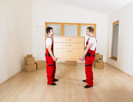 Professional movers carrying furniture through a stairwell in a Highbury flat